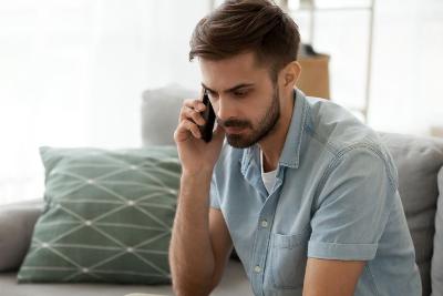 Man talking on a mobile phone while sitting on a sofa