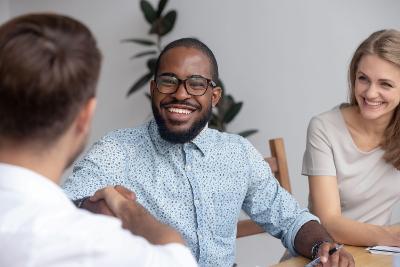A group of three people sitting at a table smiling