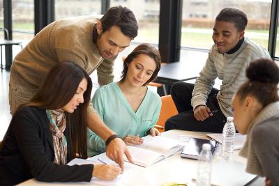 A group of people sitting and standing around a table in a meeting