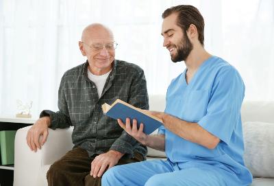 A male carer reading to an older man
